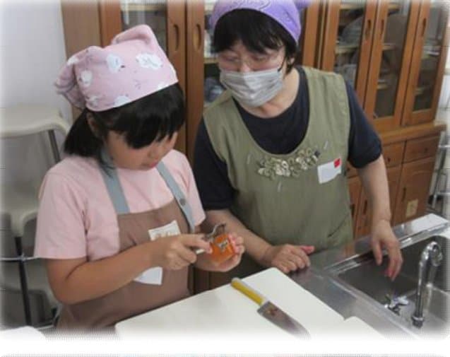 ピーラーでの皮むきを教わる子ども