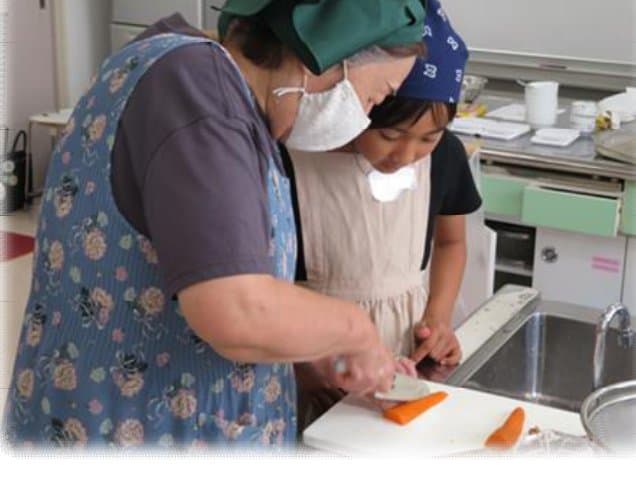 人参の切り方を教わる子ども