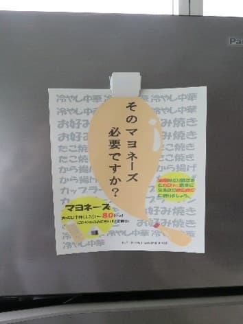 家庭の冷蔵庫に健康かわらばんを貼り付けている様子