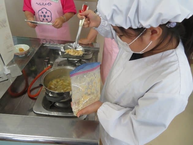 大豆を鍋に加える子どもの様子