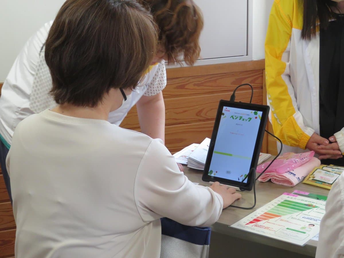 測定器に手のひらをあてて野菜摂取量を測る参加者