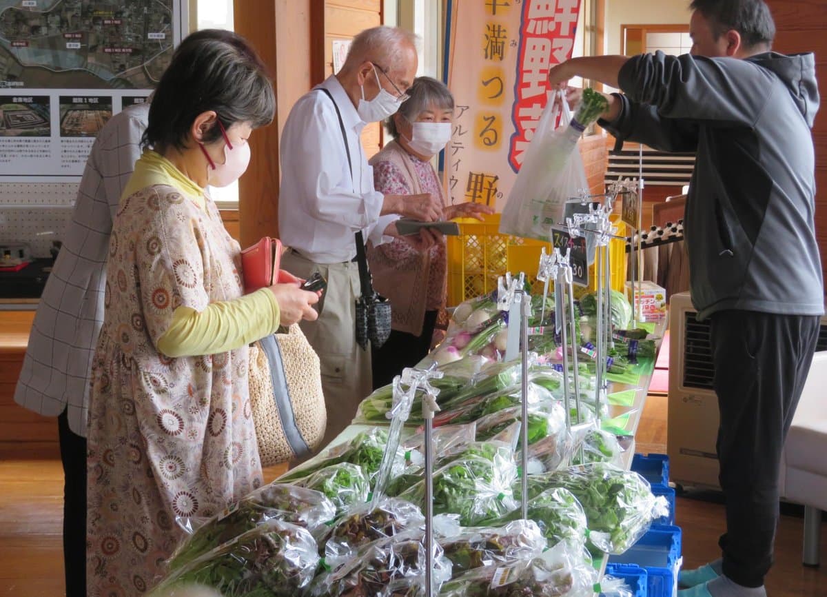 地元の野菜が並ぶ即売会で野菜を選ぶ参加者