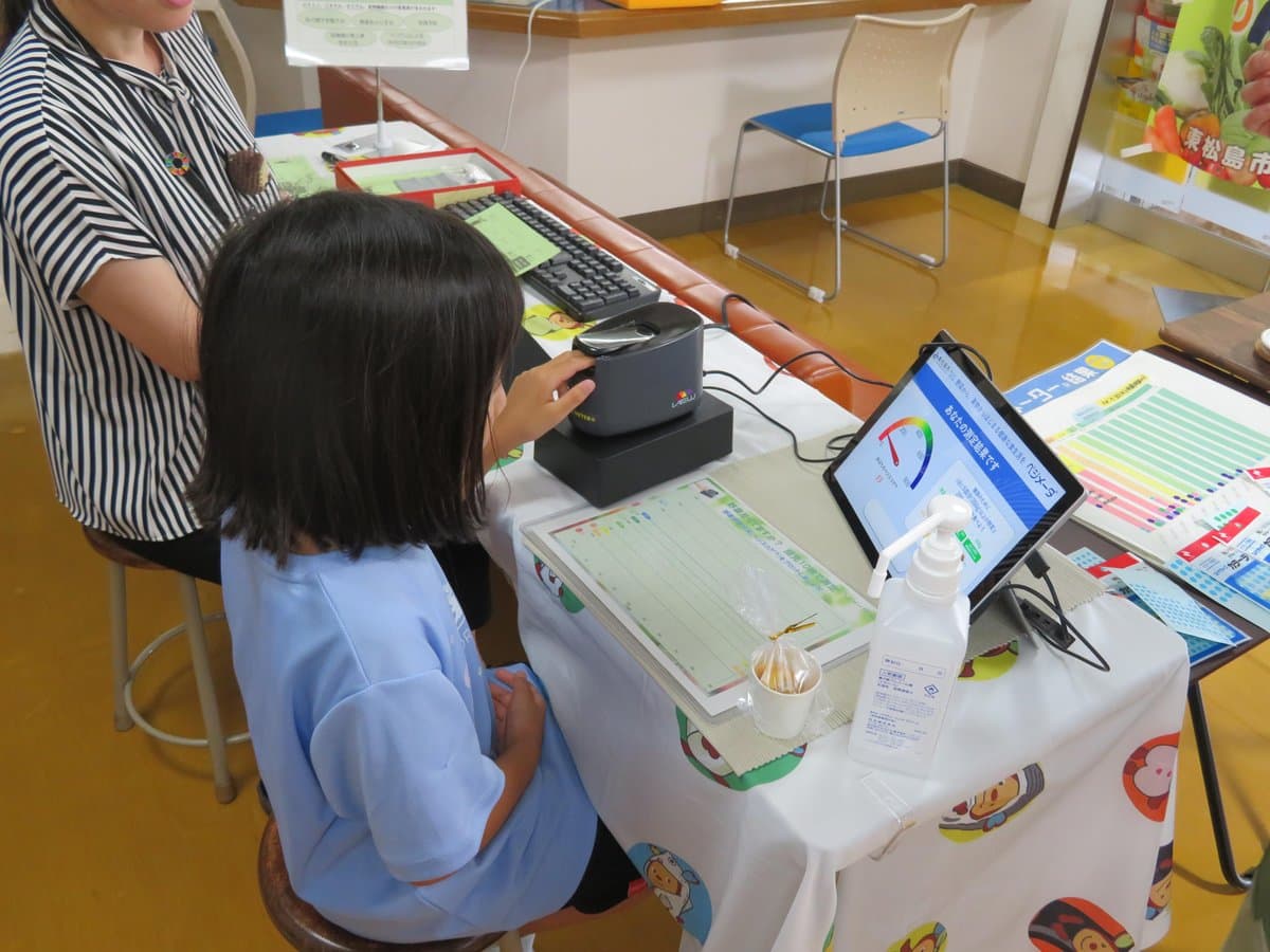 測定器に指をのせ、画面に表示された結果を見る子ども