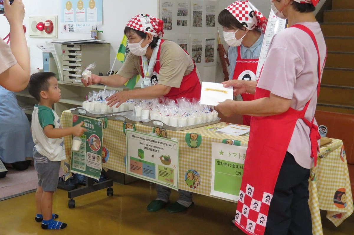 野菜入りおやつの試食を手渡される子ども